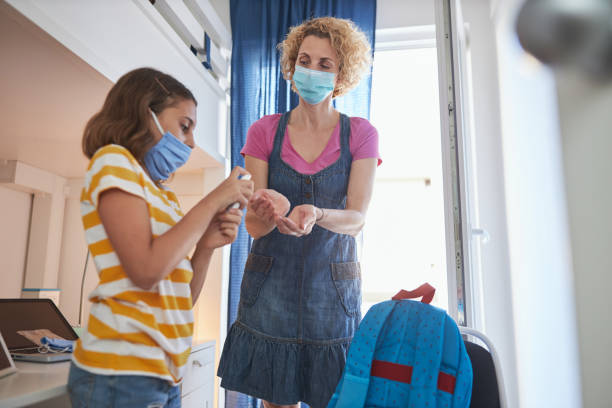 istock Spraying antiseptic solution for preventing sickness at home. Mother and daughter went back from outdoors after school. Standard health procedure in the time of pandemics. 1272100127
