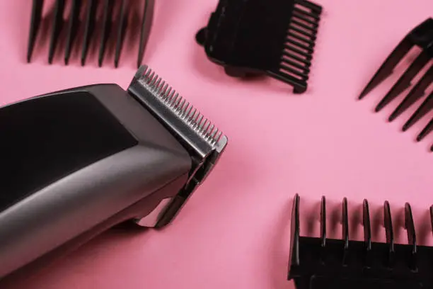 hairdressing tool, hair clipper with nozzles on a pink background close-up.