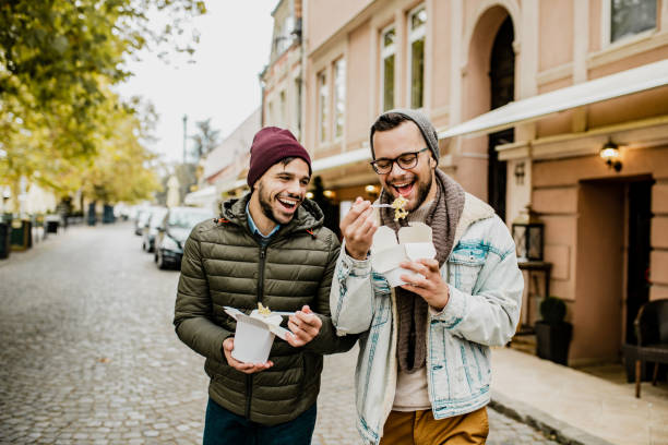 dwóch przyjaciół jedzących fast foody na świeżym powietrzu - gay man couple lifestyles homosexual zdjęcia i obrazy z banku zdjęć