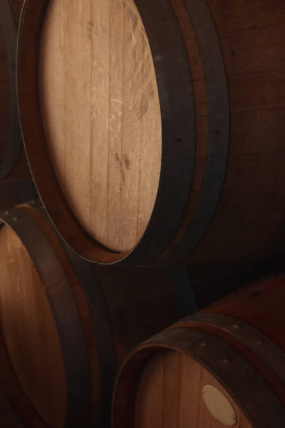 three barrels of oak wood wine stacked, with dim ground light in storage, wine cellar warehouse, in San Rafael, Mendoza province, Argentina stock photo