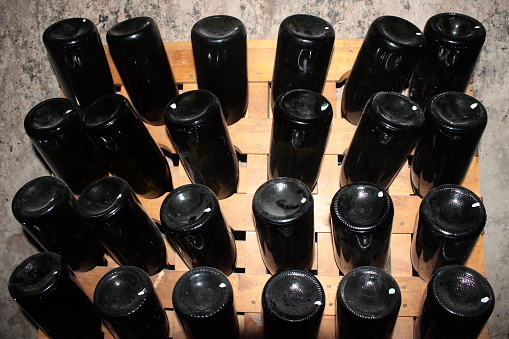 cellar of dark-colored glass wine bottles, placed so that the back of the bottle, wooden structure, is visible in a wine cellar, in the province of San Rafael, province of Mendoza, Argentina