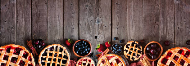 Selection of homemade autumn fruit pies. Top view border over a dark wood banner background. Selection of homemade autumn fruit pies. Top view border over a dark wood banner background with copy space. Cherry, strawberry and blueberry. at the bottom of photos stock pictures, royalty-free photos & images