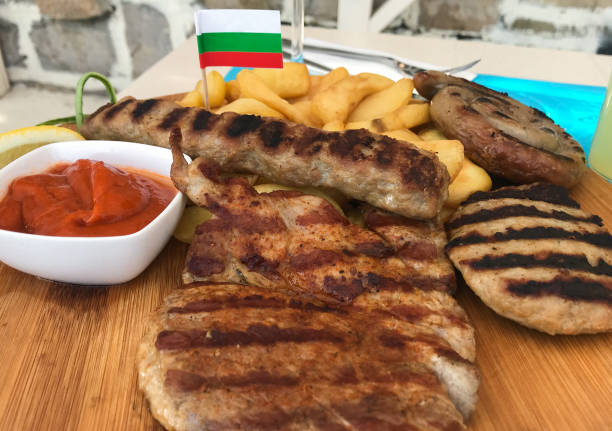 불가리아의 전국 핫 요리: "메사나 스카라"라고 불리는 다양한 구운 고기. 감자 튀김, 토마토, 고추 소스를 곁들인 나무 판에 제공됩니다. 깃발로 장식 - vastergotland 뉴스 사진 이미지