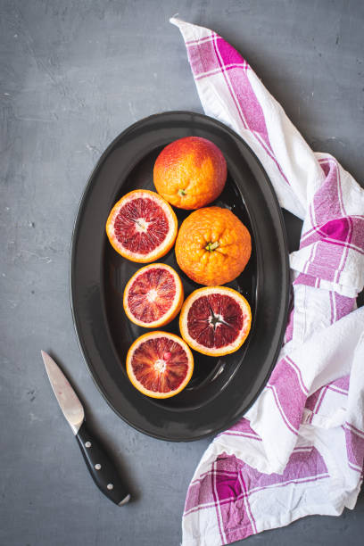 istock Fresh bloody oranges on a black plate on a dark gray background 1272115477