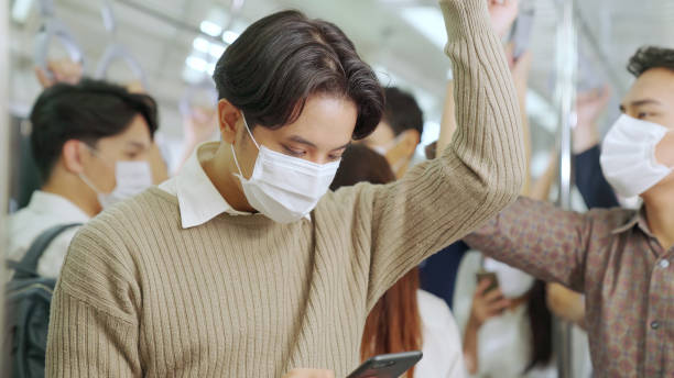 istock Traveler wearing face mask while using mobile phone on public train 1272117260