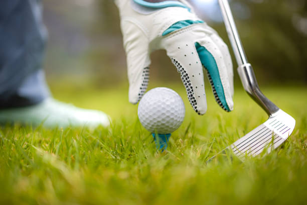 istock Hand in glove placing golf ball on tee 1272118577