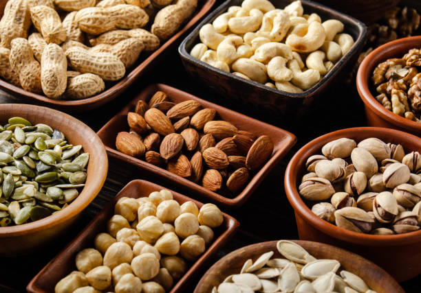 istock Assorted nuts and seeds in clay bowls on wooden kitchen table 1272120822