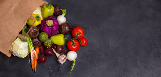 istock vegetables in a paper bag, scattered on a dark table. fresh tomatoes cucumbers pepper cabbage onions garlic. Banner with vegetables. Food delivery, organic packaging. 1272121077