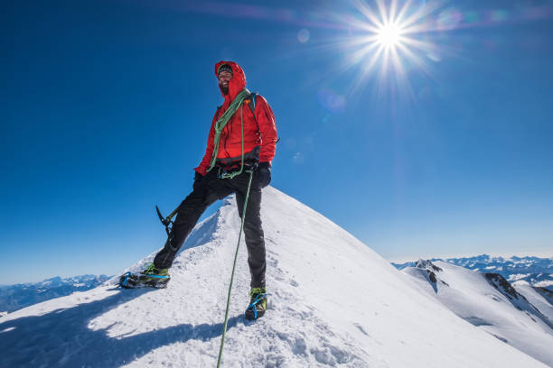 istock Last steps before Mont Blanc (Monte Bianco) summit 4,808m of smiling rope team man with climbing axe dressed mountaineering clothes,boots with crampons walking by snowy slopes with blue sky background 1272122241