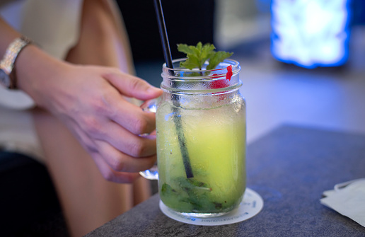 Woman having a green cocktail from a jar in a bar closeup