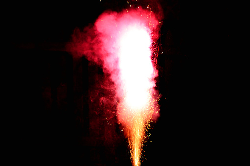 Roman candle firework emits colorful explosion, sparks, light and smoke. Plenty of room for copy on both sides.