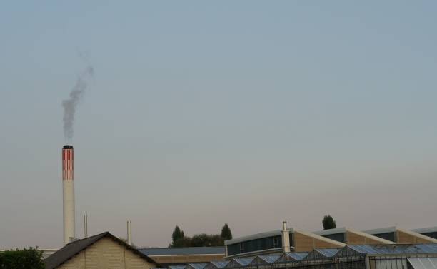 uma chaminé alta acima do bairro industrial em uma cidade na suíça. - smog city pollution town - fotografias e filmes do acervo