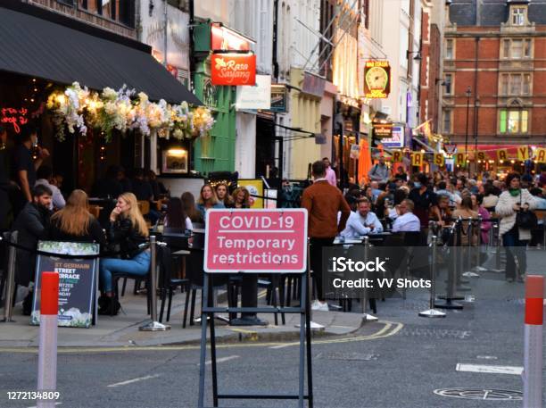 Large Group Of People In Bars And Restaurants In Soho At Night With Covid19 Sign London Stock Photo - Download Image Now