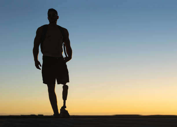 silhouette des athletischen mannes mit prothetischem bein mit sonnenuntergang steilhimmel im hintergrund - amputiert stock-fotos und bilder