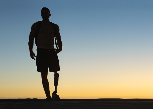 Silueta del hombre atlético con pierna protésica con cielo al atardecer en el fondo photo