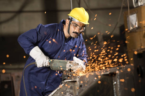 istock Mechanic using circular saw grinder tool with protective work wear at factory 1272135024