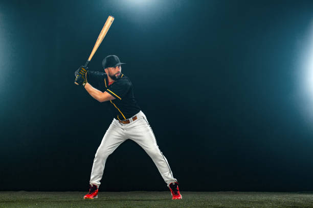 istock Baseball player with bat on dark background. Ballplayer portrait. 1272135961
