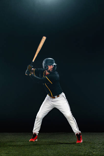 istock Baseball player with bat on dark background. Ballplayer portrait. 1272136016