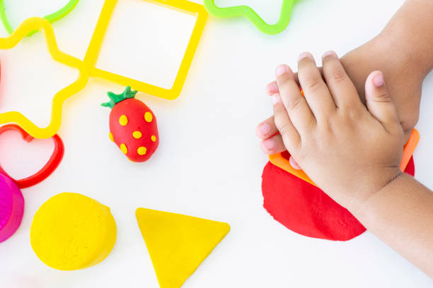 istock Toddler sculpts from colored plasticine on a white table. Childrens creativity, educational games, fine motor skills 1272137840