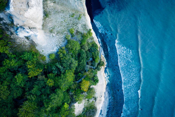 Pandangan mata drone melihat langsung ke tepi air di mana tangga 497 mencapai dasar tebing. Difoto pada awal musim gugur di pulau Moen di Denmark. Warna, horizontal dengan beberapa ruang salin.