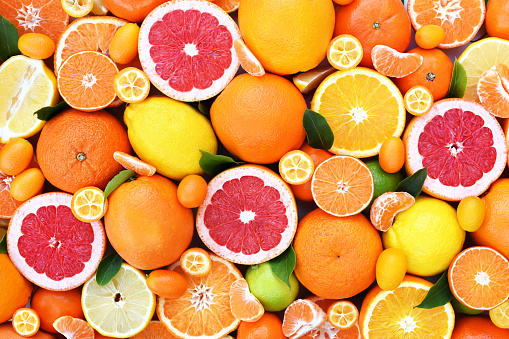 Colorful bright background of fresh ripe sweet citrus fruits: orange and red grapefruit, green lime and yellow lemon, tangerine and kumquat