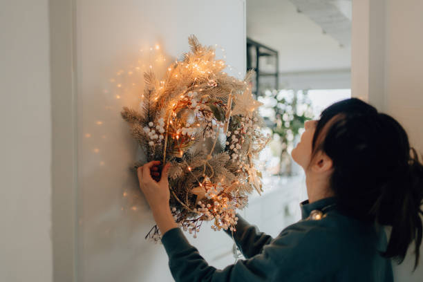 young woman decorating her living room for the upcoming holidays - decorating imagens e fotografias de stock