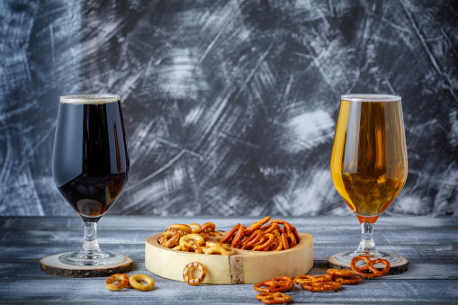 Salty snacks, pretzels and two glasses of dark and light beer. Negative space. Copy space.