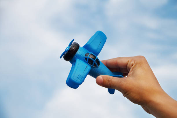 istock toy blue plane in a man's hand on a blue background with clouds sky 1272153348