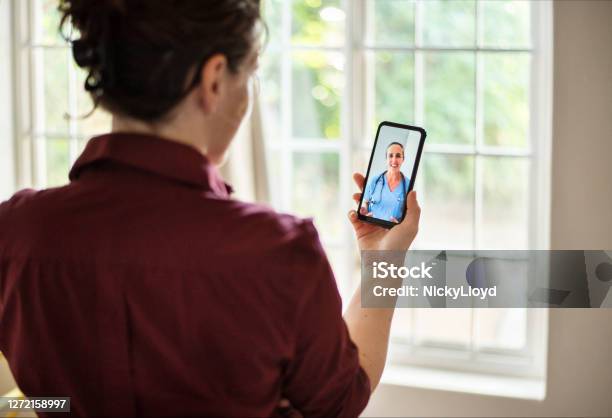Woman Consulting Her Doctor Using An App On Her Smart Phone Stock Photo - Download Image Now