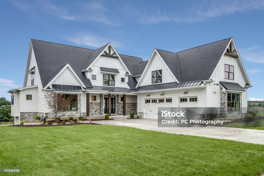 Large house with steep roof and side entry three car garage Beautiful design and detail on new home House Stock Photo