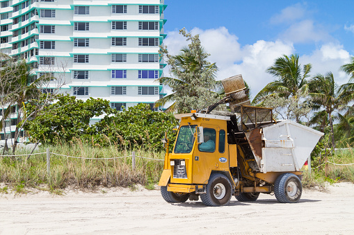 Tractor collecting the trash and cleaning up the sand the beach in Miami Beach, Florida, USA.