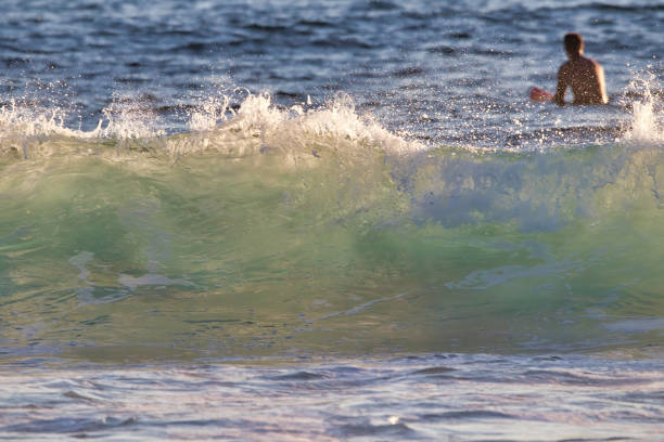 istock Surfer watching for the next wave just beyond a BEAUTIFUL AQUAMARINE WAVE BREAKING NEAR SHORE. 1272166383