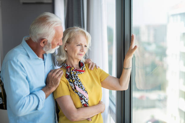 istock Senior couple looking through window at home. 1272170570