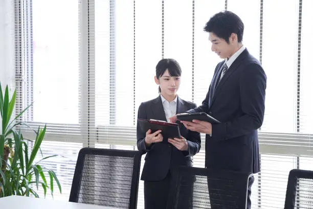 Japanese businesspersons sit at the office window looking at documents