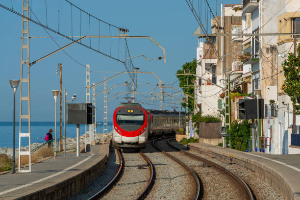 Arrival of the train at the station of the city of San Pol de Mar An electric train arrives at the train station of the small Catalan resort town of Sant Pol de Mar on June 5, 2014. The railway line runs along the coastline. This route is popular with tourists from Spain and all over the world. san pol de mar stock pictures, royalty-free photos & images