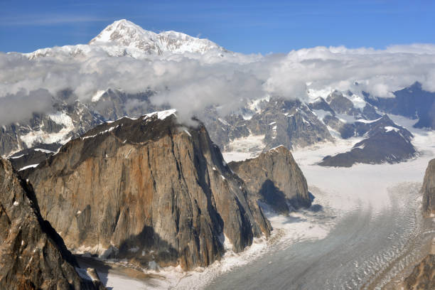 Mount Denali (formerly Mount McKinley) towering above the Great Gorge of the Ruth Glacier, Denali National Park, Alaska, USA. Mount Denali is the highest peak in North America with an elevation of 20,310 feet (6,190 m) above sea level. The colorful mountain in the foreground is Mt Dickey (9,545 ft /2,909 m) notable for its east face, which has a vertical mile (1600 m) of sheer granite. This is one of the tallest rock walls in the world.