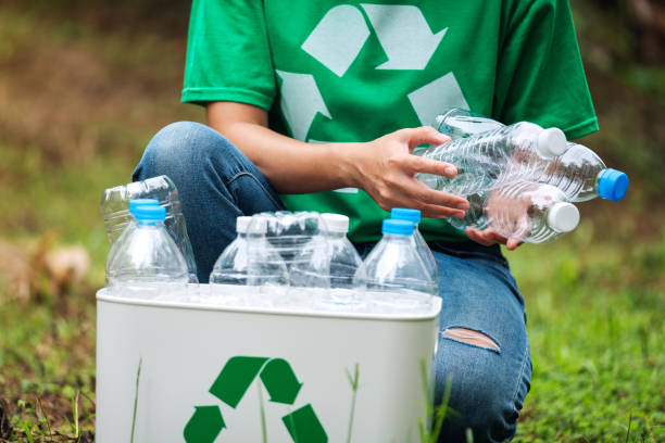 istock A woman collecting and putting plastic bottles into a recycle bin 1272183936
