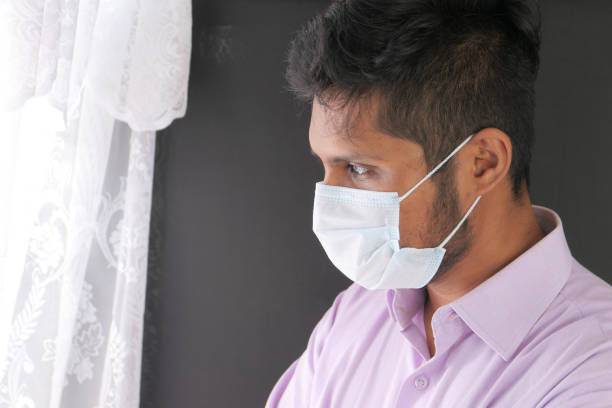 istock A young asian man with protective mask in face looking through window 1272189626
