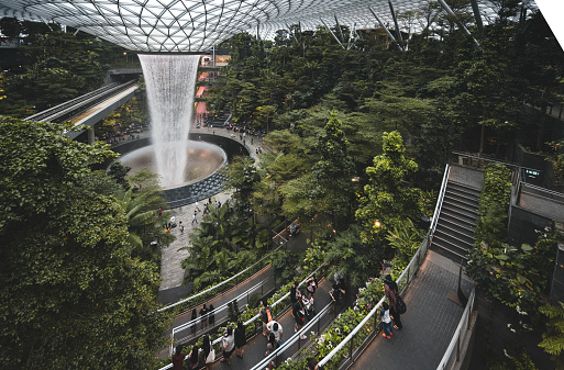 Singapore, September 6, 2020: People watching a spectacular waterfall inside the Changi Airport in Singapore. The waterfall is located inside the Jewels shopping mall in Terminal 1 and Terminal 2.
