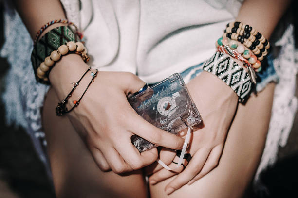 immagine ravvicinata dell'audiocassetta tenuta in mano a giovani donne hippie che indossano abiti e accessori bianchi in stile boho - turkish culture audio foto e immagini stock