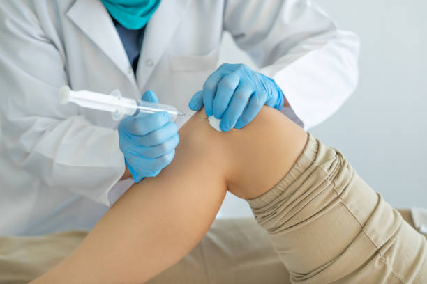 therapist applying ozone injection to patient's knee - injetar imagens e fotografias de stock