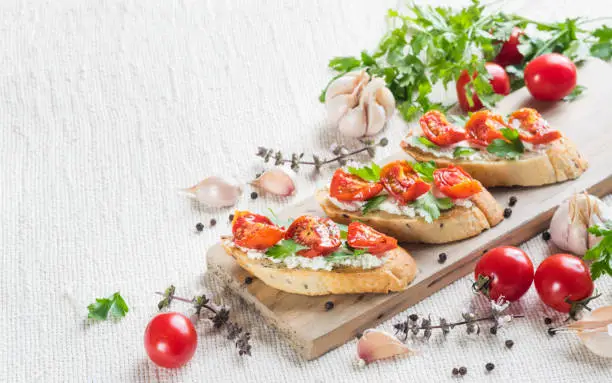 Italian bruschetta with tomatoes and greens on wooden cuting board, horizontal orientation, copyspace