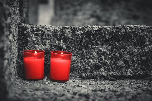 Two red candles on a grave. Lanterns on a tombstone at All Saints' Day in a cemetery. Shallow depth of field. Religion, funeral, mourning concept.