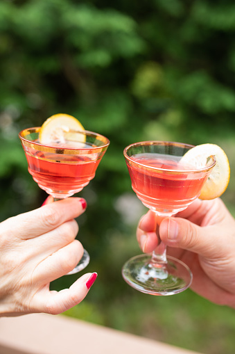 A senior Japanese man and woman are toasting their cocktail glasses outside.