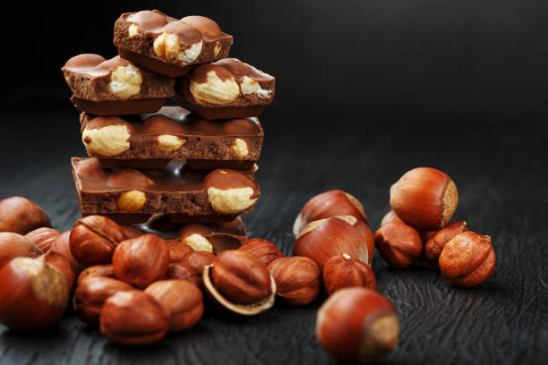 istock Chocolate with hazelnuts in the form of a tower on a dark background, surrounded by nuts in the shell and peeled. 1272207176