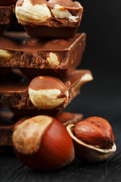 istock Chocolate with hazelnuts in the form of a tower on a dark background, surrounded by nuts in the shell and peeled. 1272207199