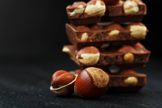 istock Chocolate with hazelnuts in the form of a tower on a dark background, surrounded by nuts in the shell and peeled. 1272207206