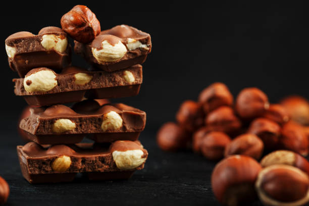 istock Chocolate with hazelnuts in the form of a tower on a dark background, surrounded by nuts in the shell and peeled. 1272207242