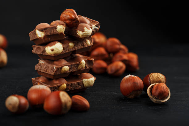 istock Chocolate with hazelnuts in the form of a tower on a dark background, surrounded by nuts in the shell and peeled. 1272207251