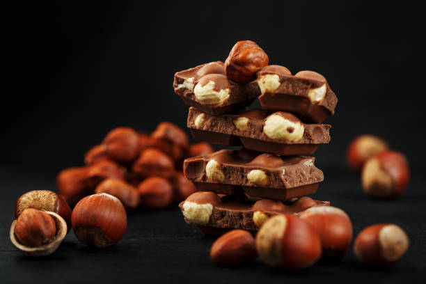 istock Chocolate with hazelnuts in the form of a tower on a dark background, surrounded by nuts in the shell and peeled. 1272207258